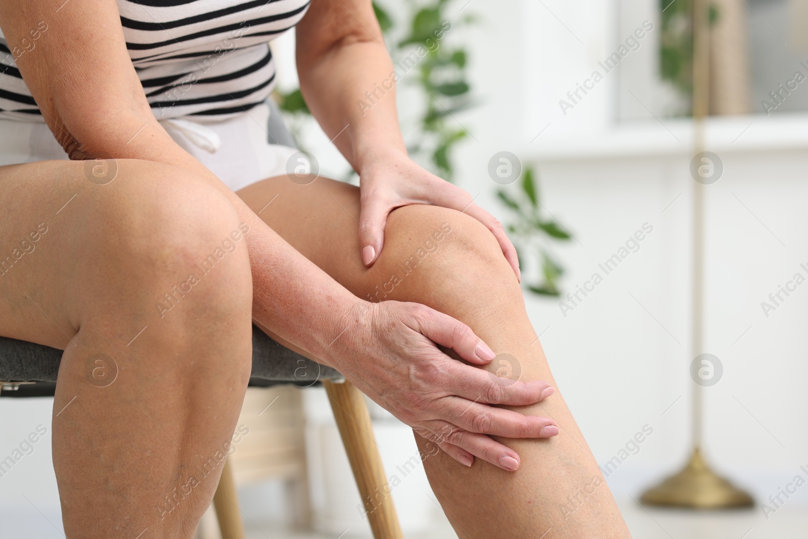 Photo of Woman suffering from pain in her knee at home, closeup. Space for text