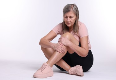 Photo of Senior woman suffering from knee pain on white background