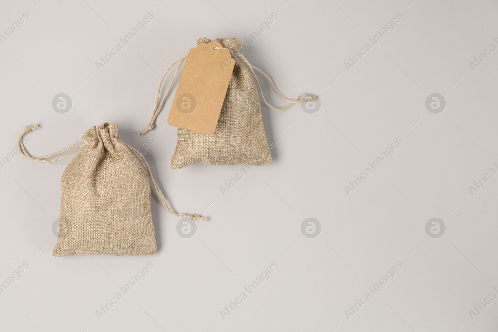 Photo of Burlap bags on light grey background, flat lay. Space for text