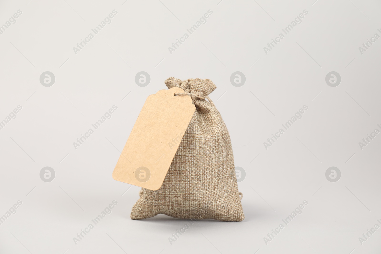 Photo of One burlap bag with tag on light background