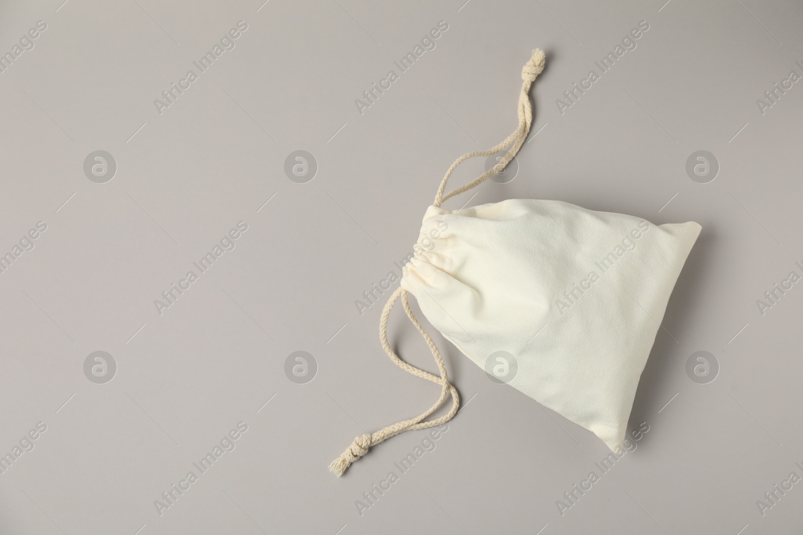 Photo of White cotton bag with ties on light grey background, top view. Space for text