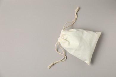 Photo of White cotton bag with ties on light grey background, top view. Space for text