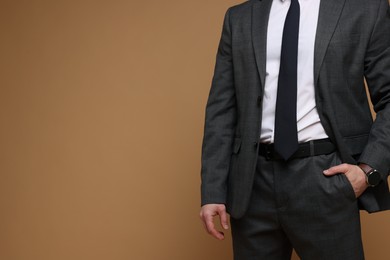 Photo of Man in classic suit on brown background, closeup. Space for text