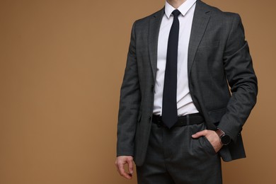 Man in classic suit on brown background, closeup. Space for text