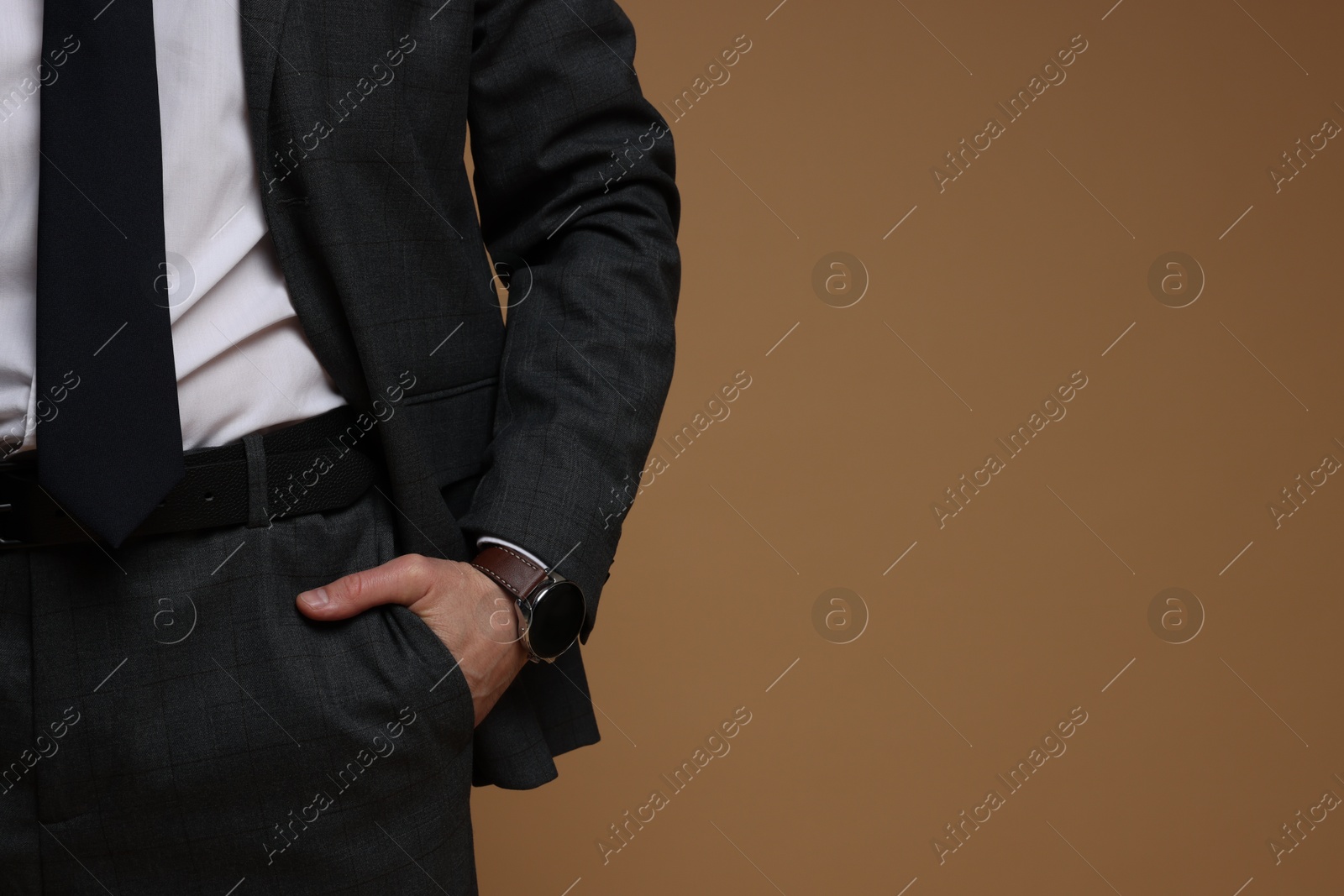 Photo of Man in classic suit on brown background, closeup. Space for text