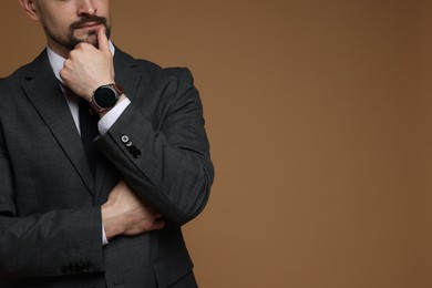 Photo of Man in classic suit on brown background, closeup. Space for text