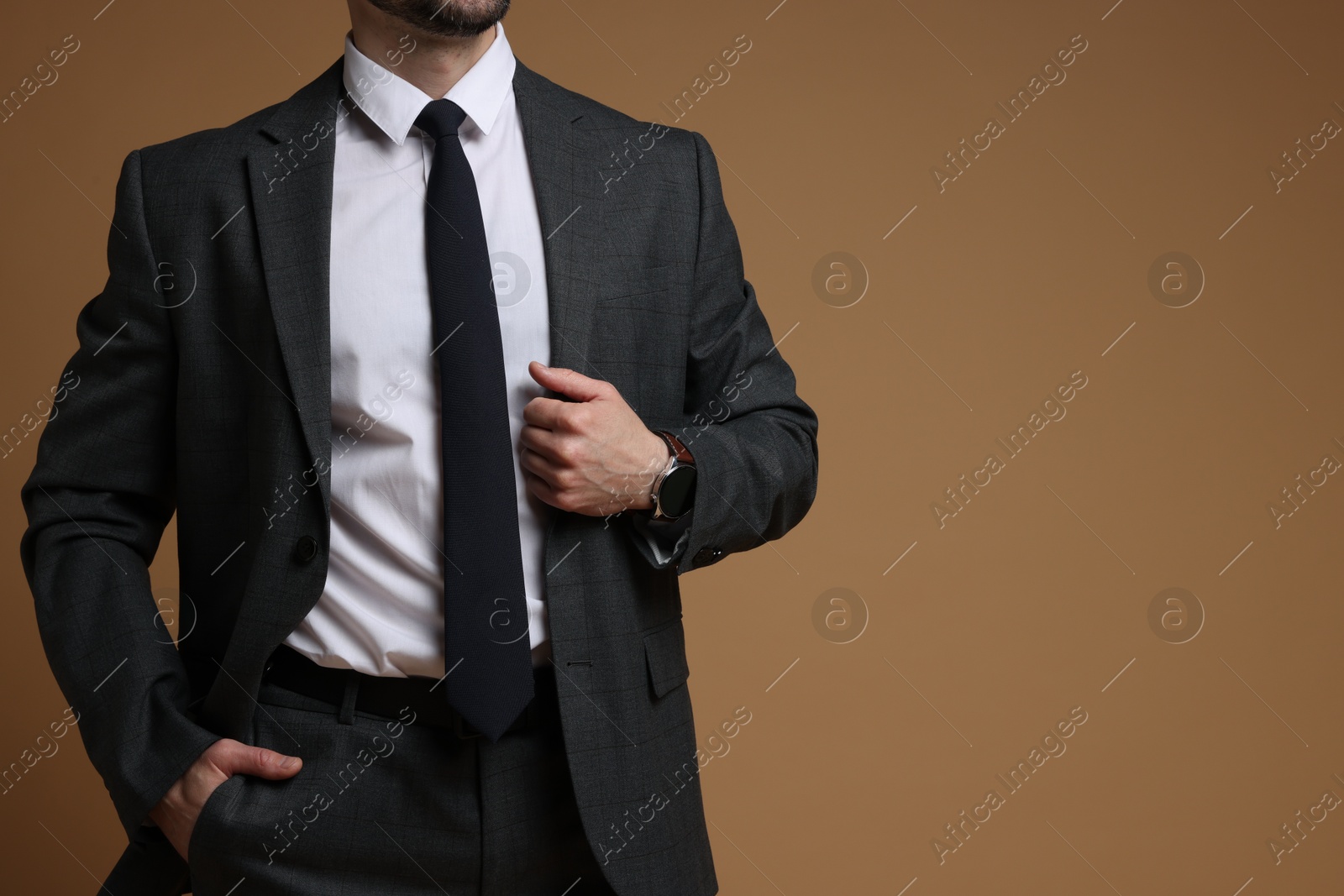 Photo of Man in classic suit on brown background, closeup. Space for text