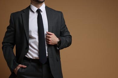 Photo of Man in classic suit on brown background, closeup. Space for text