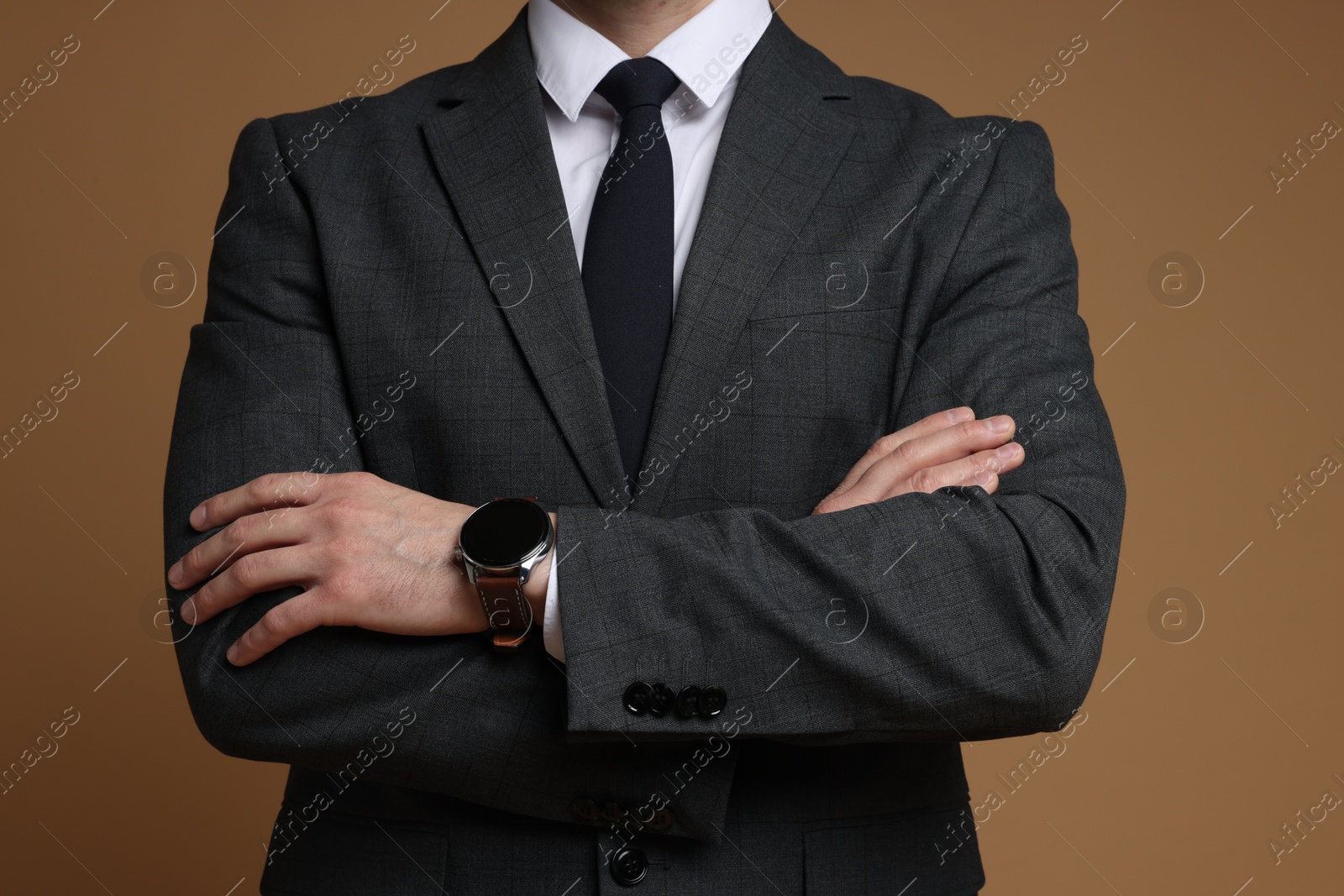 Photo of Man in classic suit with stylish watch on brown background, closeup