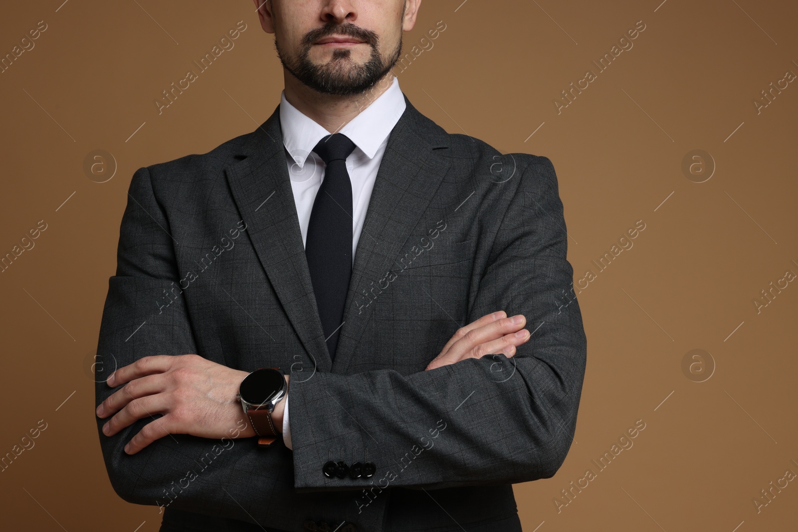 Photo of Man in classic suit with stylish watch on brown background, closeup