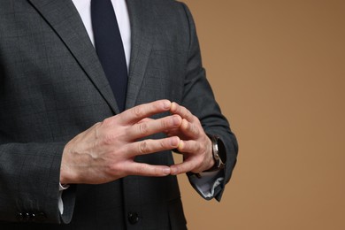 Photo of Man in classic suit on brown background, closeup. Space for text