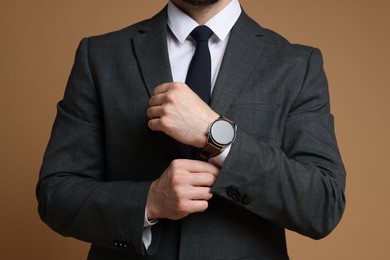 Photo of Man in classic suit with stylish watch on brown background, closeup