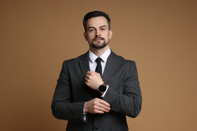 Photo of Confident man in classic suit with stylish watch on brown background