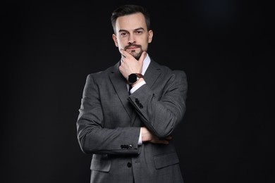 Photo of Confident man in classic suit on black background