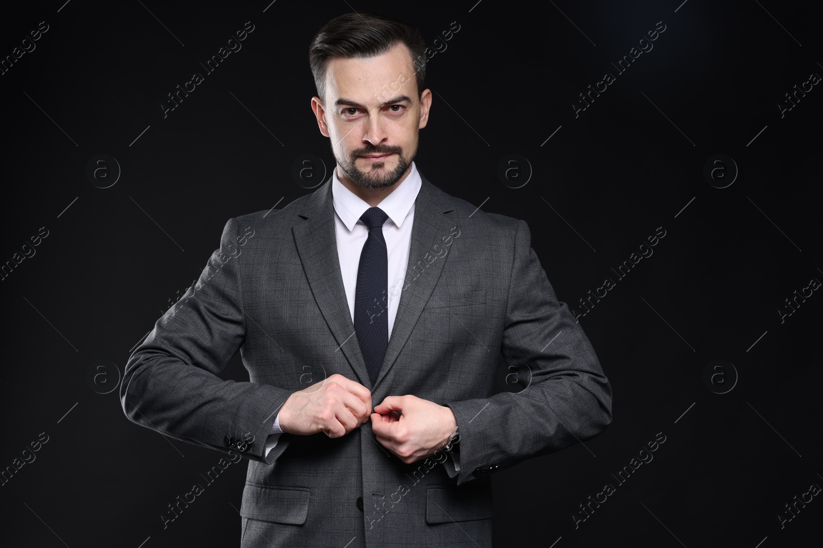 Photo of Confident man in classic suit on black background