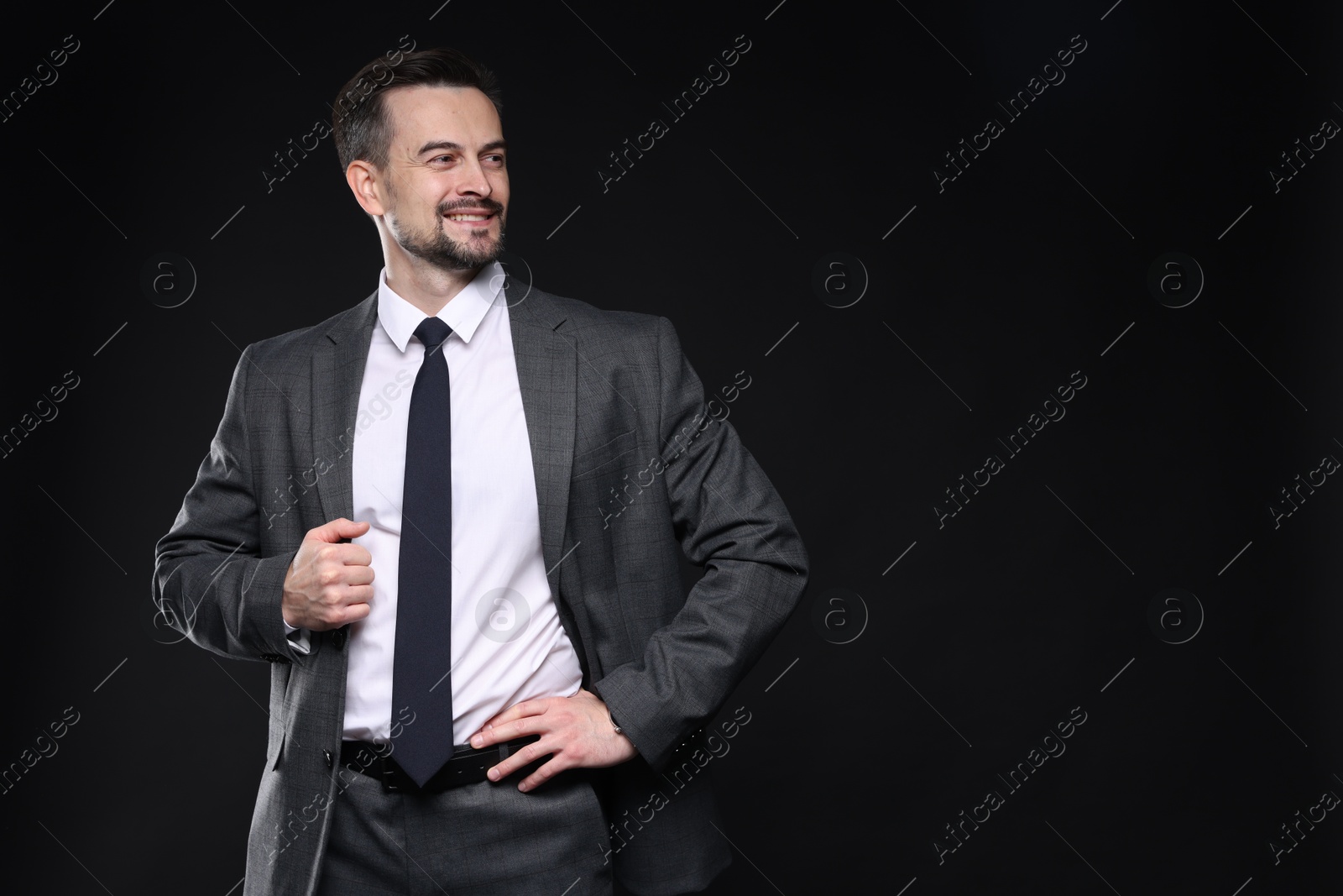 Photo of Confident man in classic suit on black background. Space for text