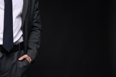 Photo of Man in classic suit on black background, closeup. Space for text