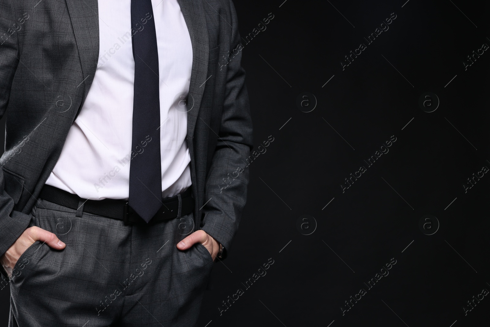 Photo of Man in classic suit on black background, closeup. Space for text