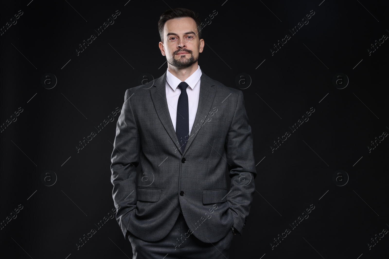 Photo of Confident man in classic suit on black background