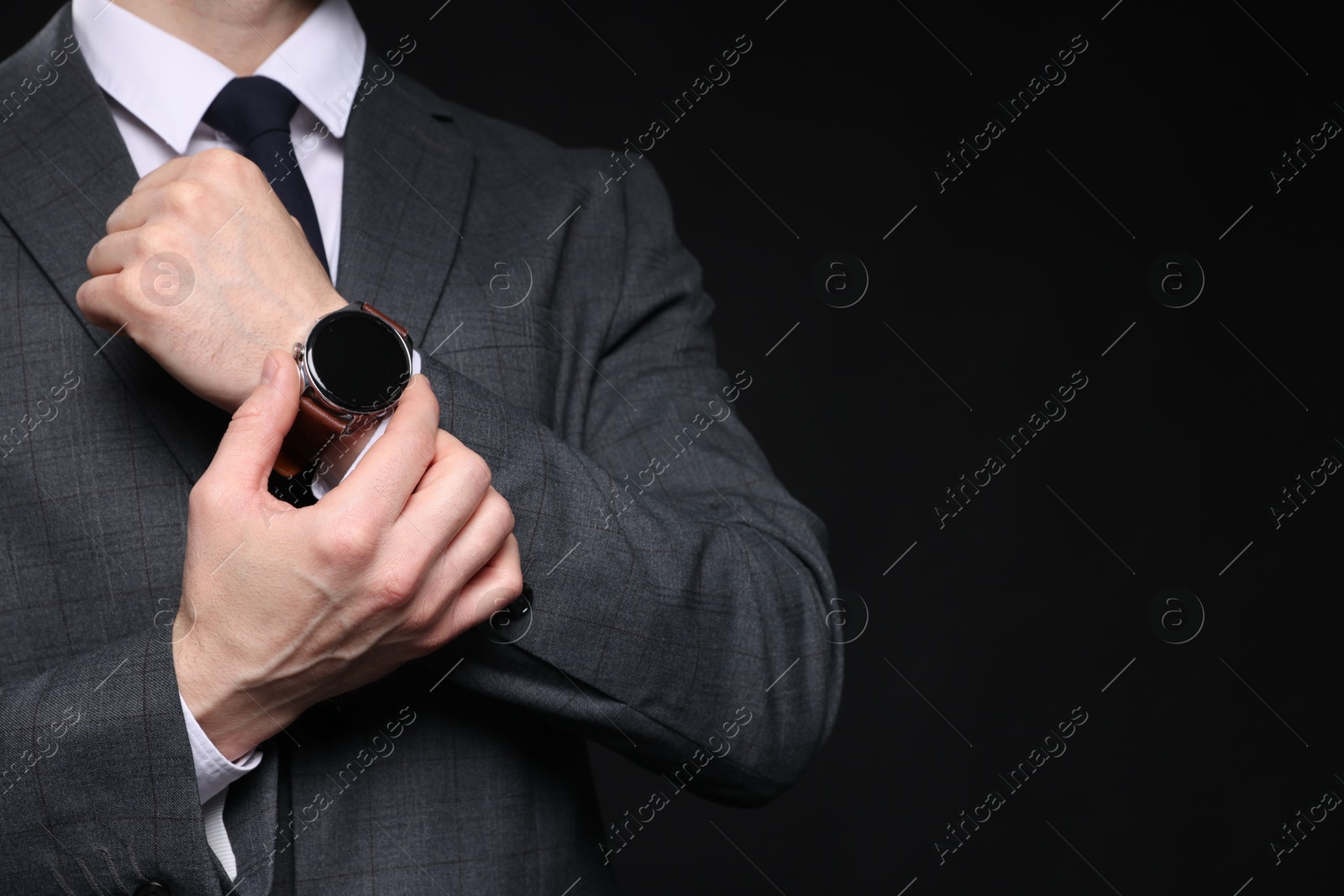 Photo of Man in classic suit with stylish watch on black background, closeup. Space for text