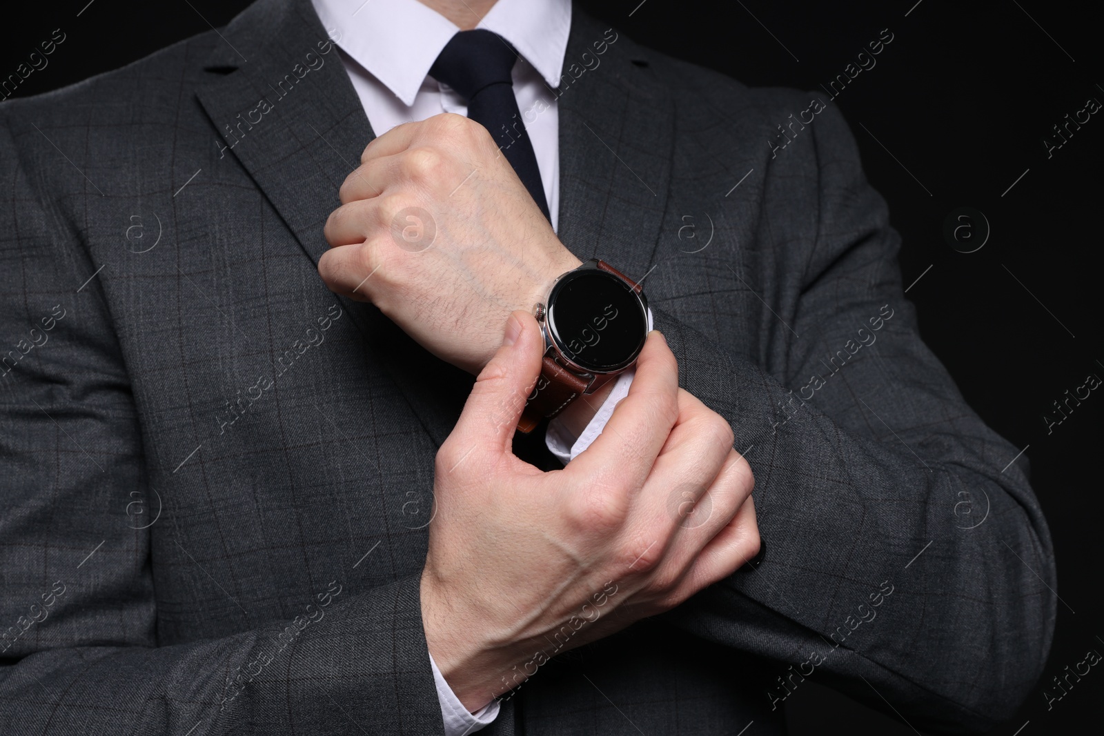 Photo of Man in classic suit with stylish watch on black background, closeup