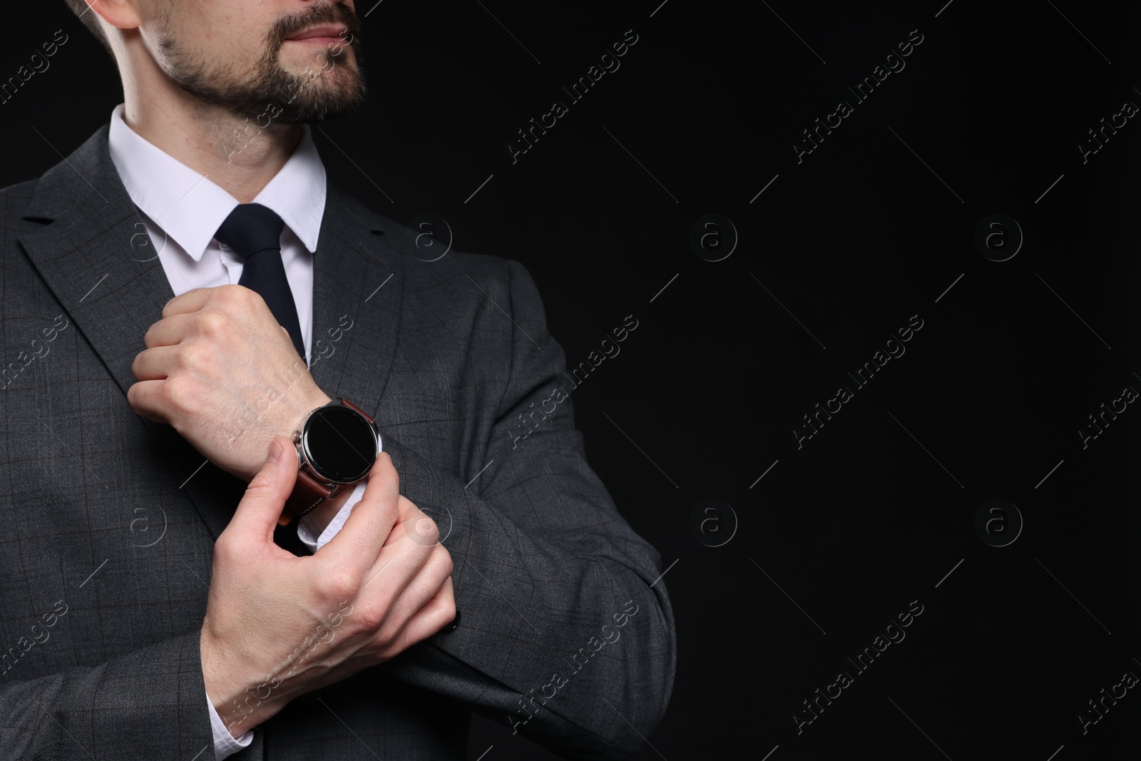 Photo of Man in classic suit with stylish watch on black background, closeup. Space for text