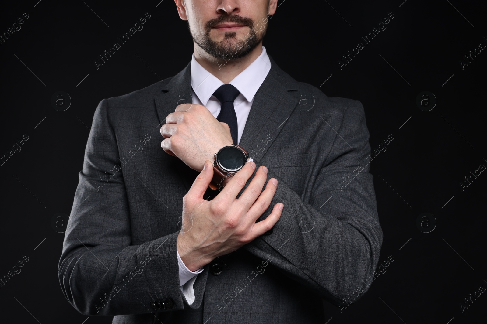 Photo of Man in classic suit with stylish watch on black background, closeup