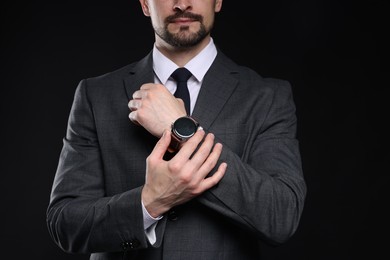 Photo of Man in classic suit with stylish watch on black background, closeup