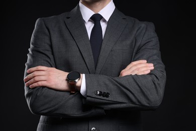 Photo of Man in classic suit with stylish watch on black background, closeup