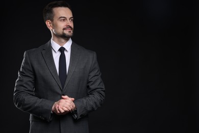 Photo of Confident man in classic suit on black background. Space for text