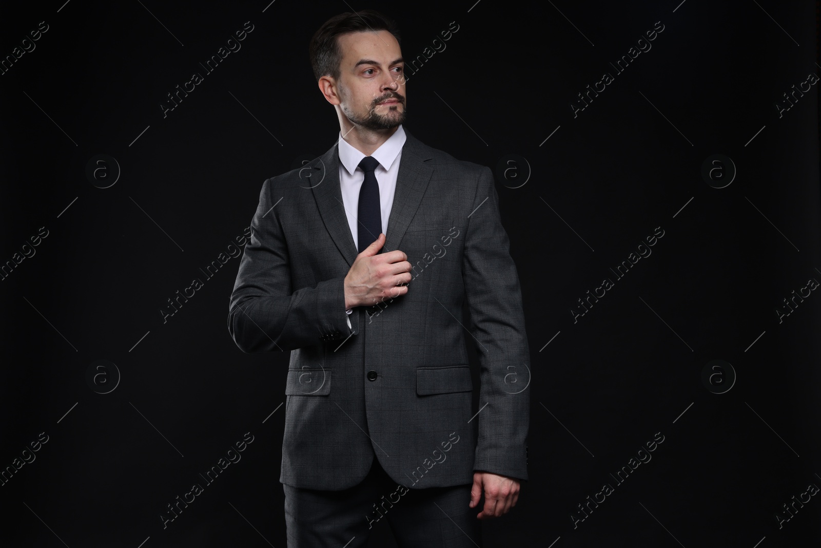 Photo of Confident man in classic suit on black background