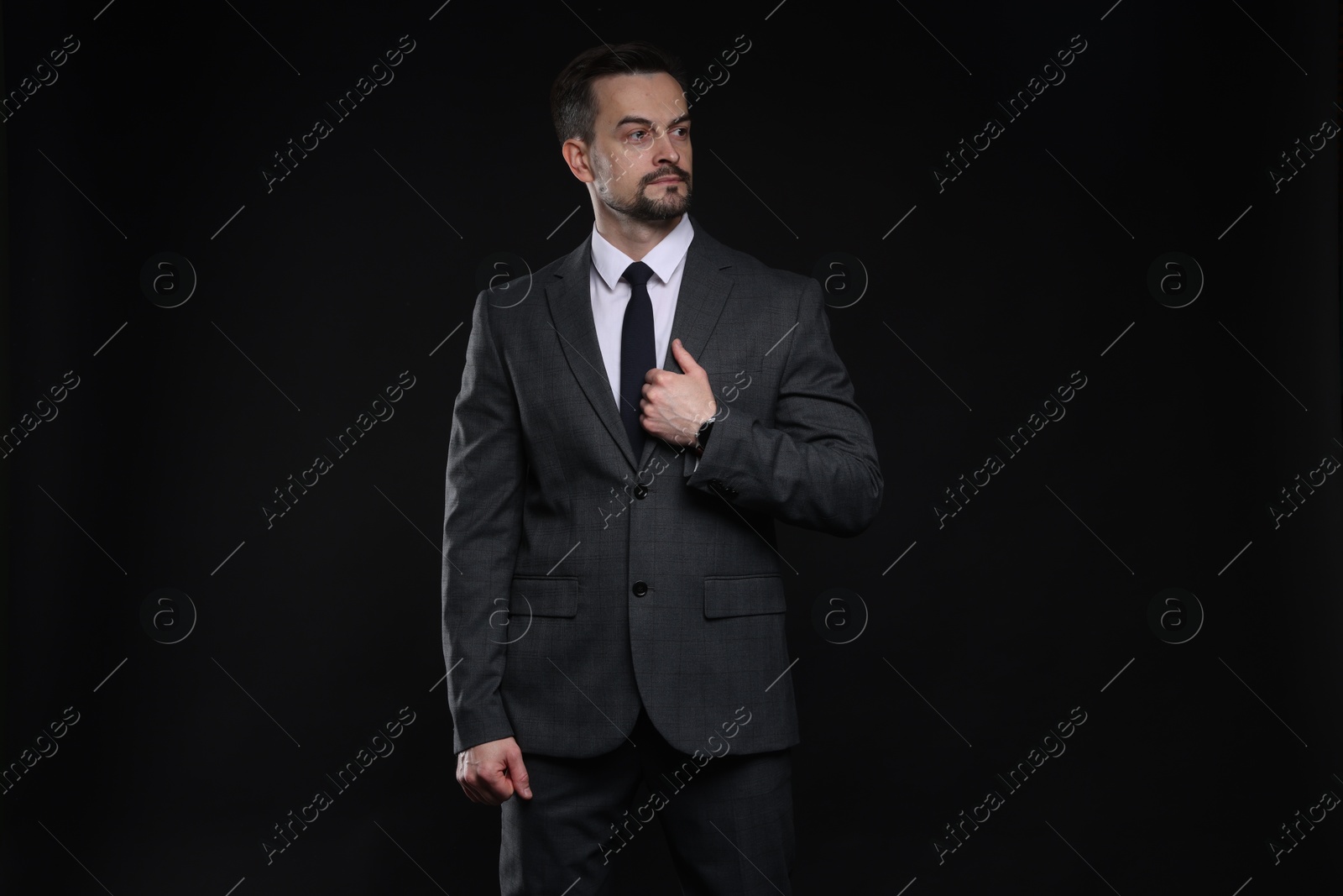 Photo of Confident man in classic suit on black background