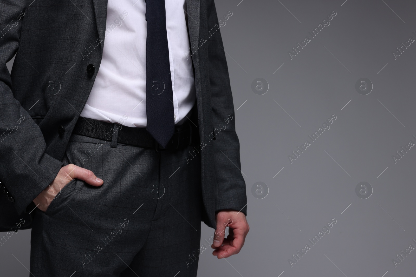 Photo of Man in classic suit on grey background, closeup. Space for text