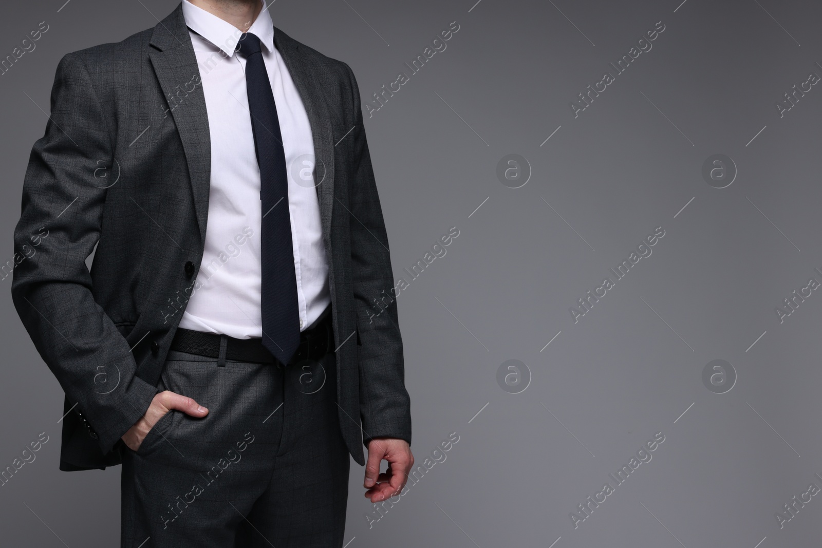 Photo of Man in classic suit on grey background, closeup. Space for text