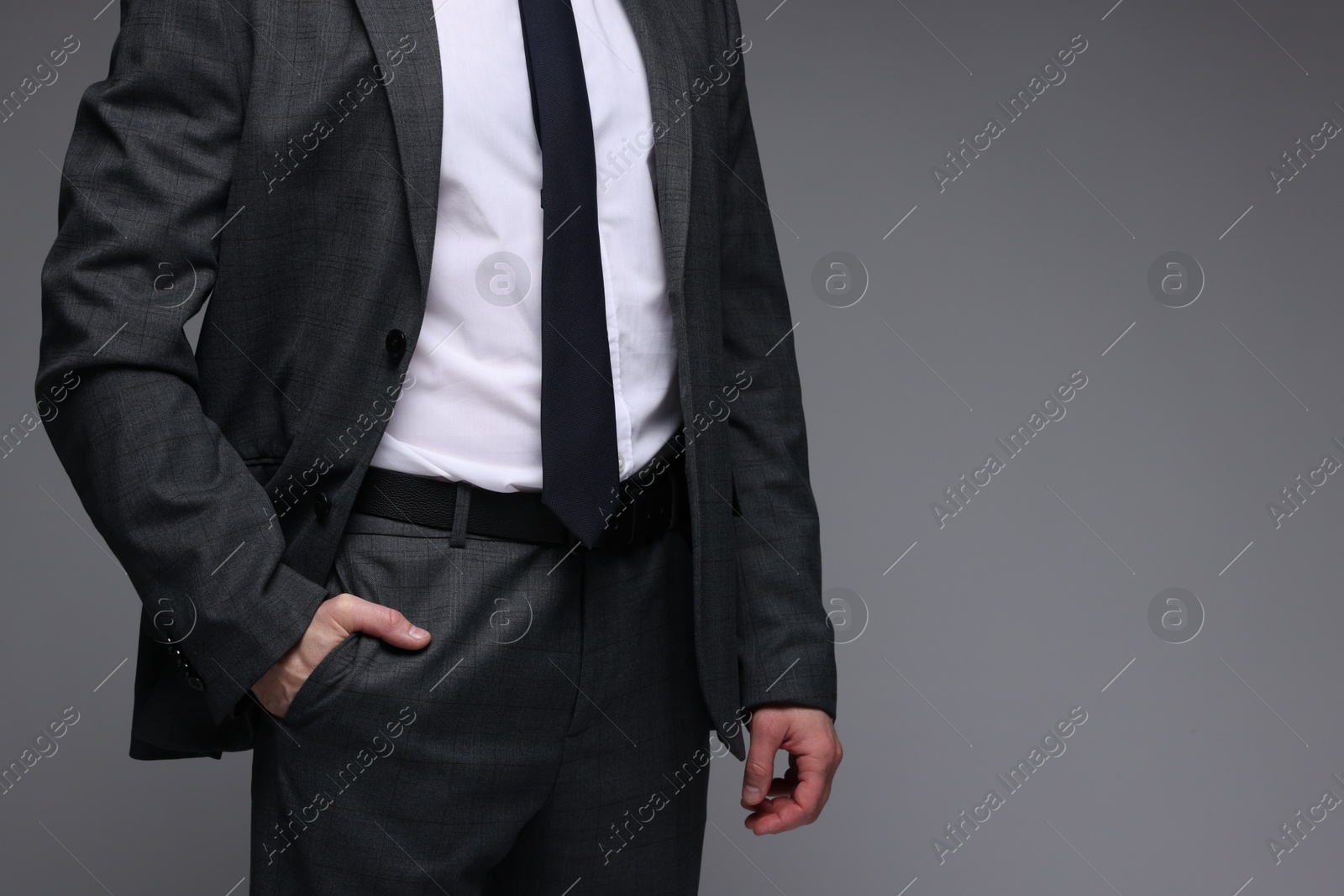 Photo of Man in classic suit on grey background, closeup. Space for text