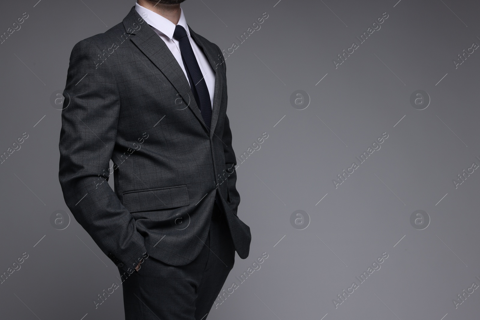 Photo of Man in classic suit on grey background, closeup. Space for text