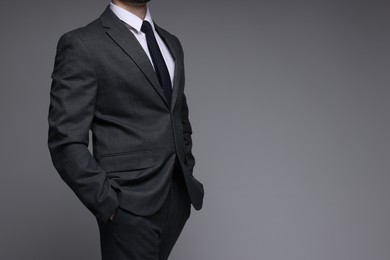 Photo of Man in classic suit on grey background, closeup. Space for text