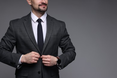 Photo of Man in classic suit on grey background, closeup. Space for text