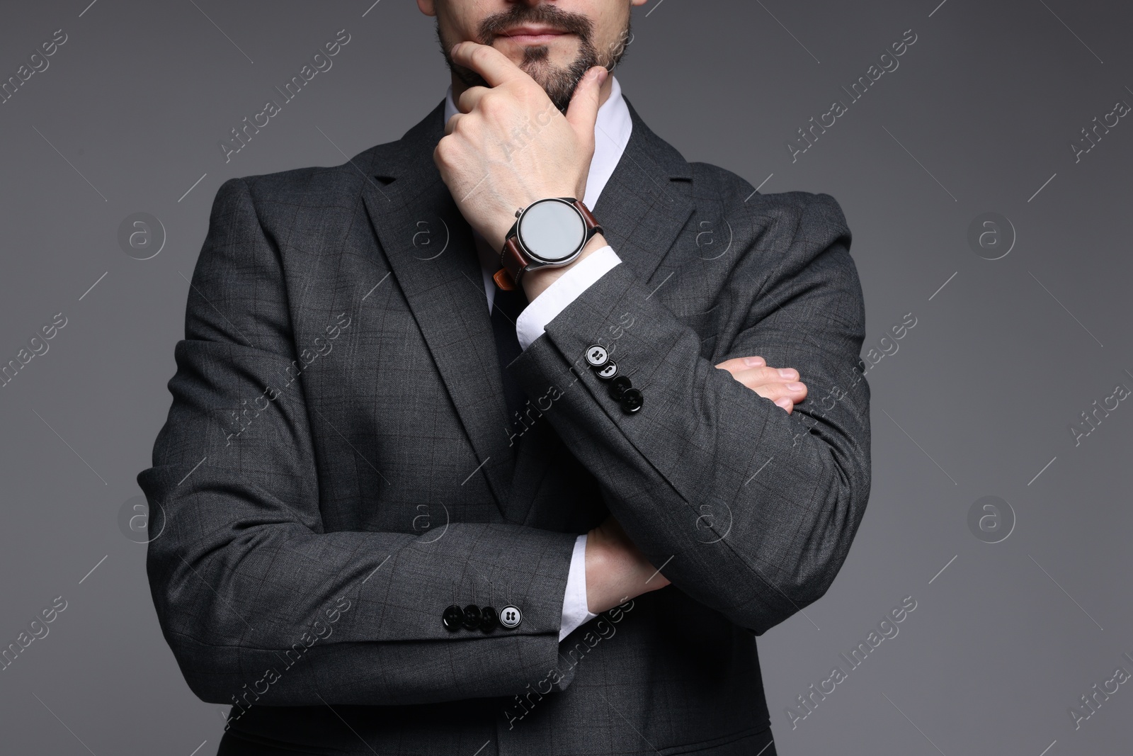 Photo of Man in classic suit with stylish watch on grey background, closeup