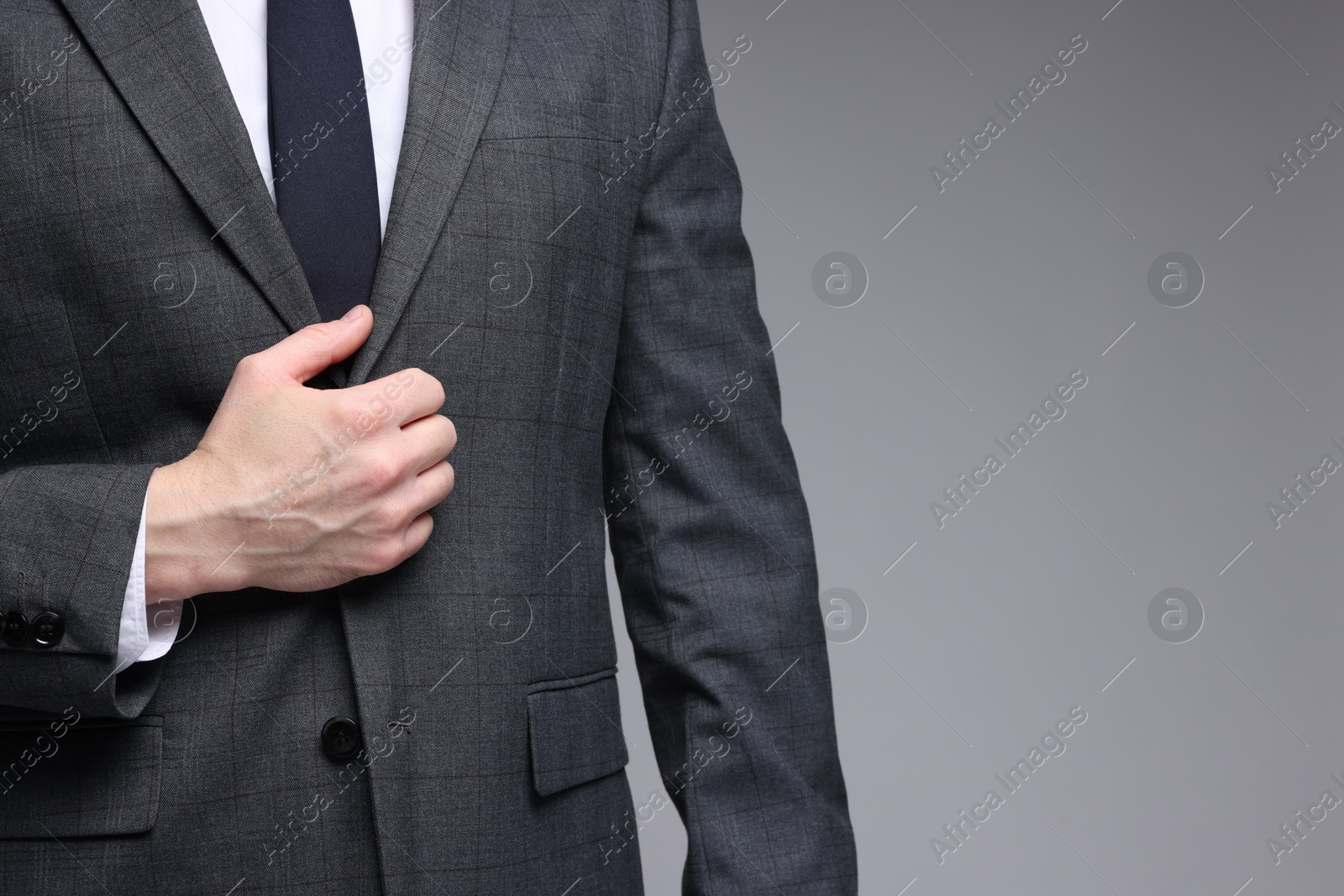 Photo of Man in classic suit on grey background, closeup. Space for text