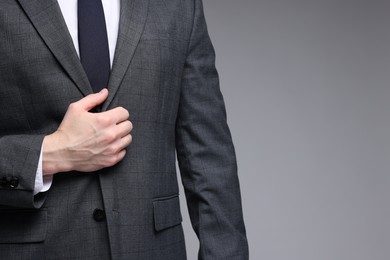 Photo of Man in classic suit on grey background, closeup. Space for text