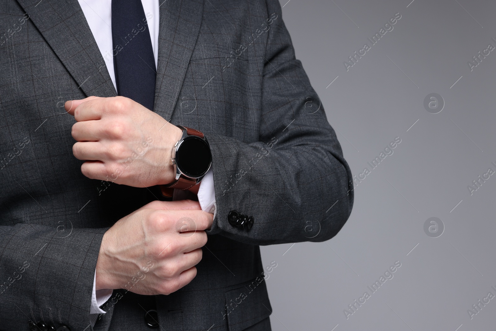 Photo of Man in classic suit with stylish watch on grey background, closeup. Space for text