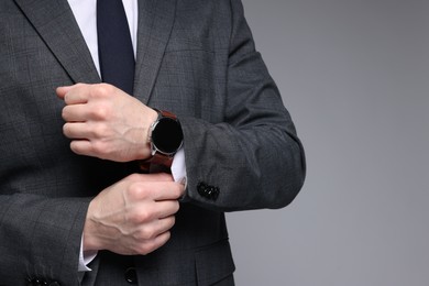 Photo of Man in classic suit with stylish watch on grey background, closeup. Space for text