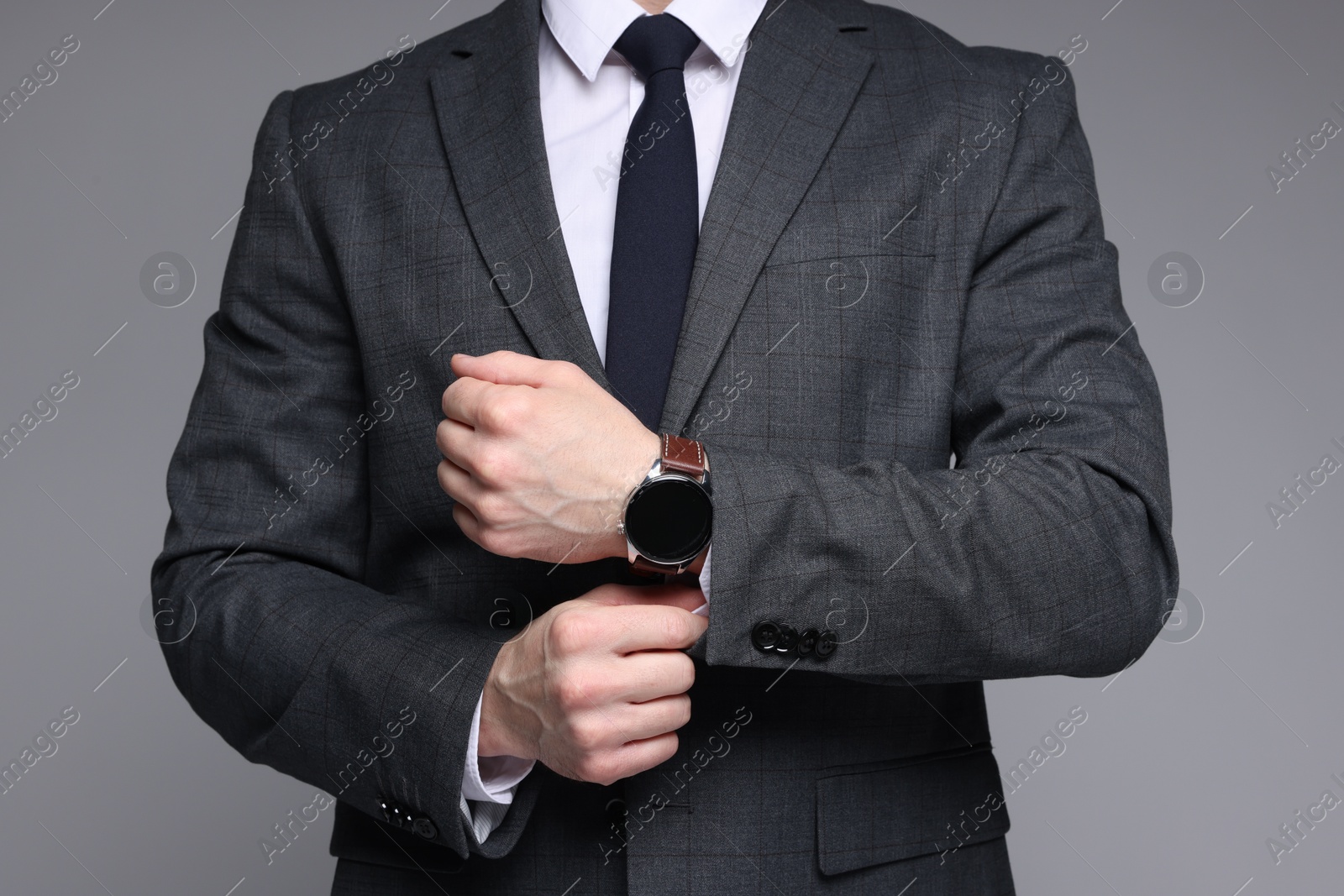 Photo of Man in classic suit with stylish watch on grey background, closeup