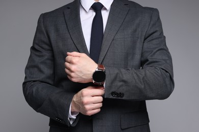 Photo of Man in classic suit with stylish watch on grey background, closeup