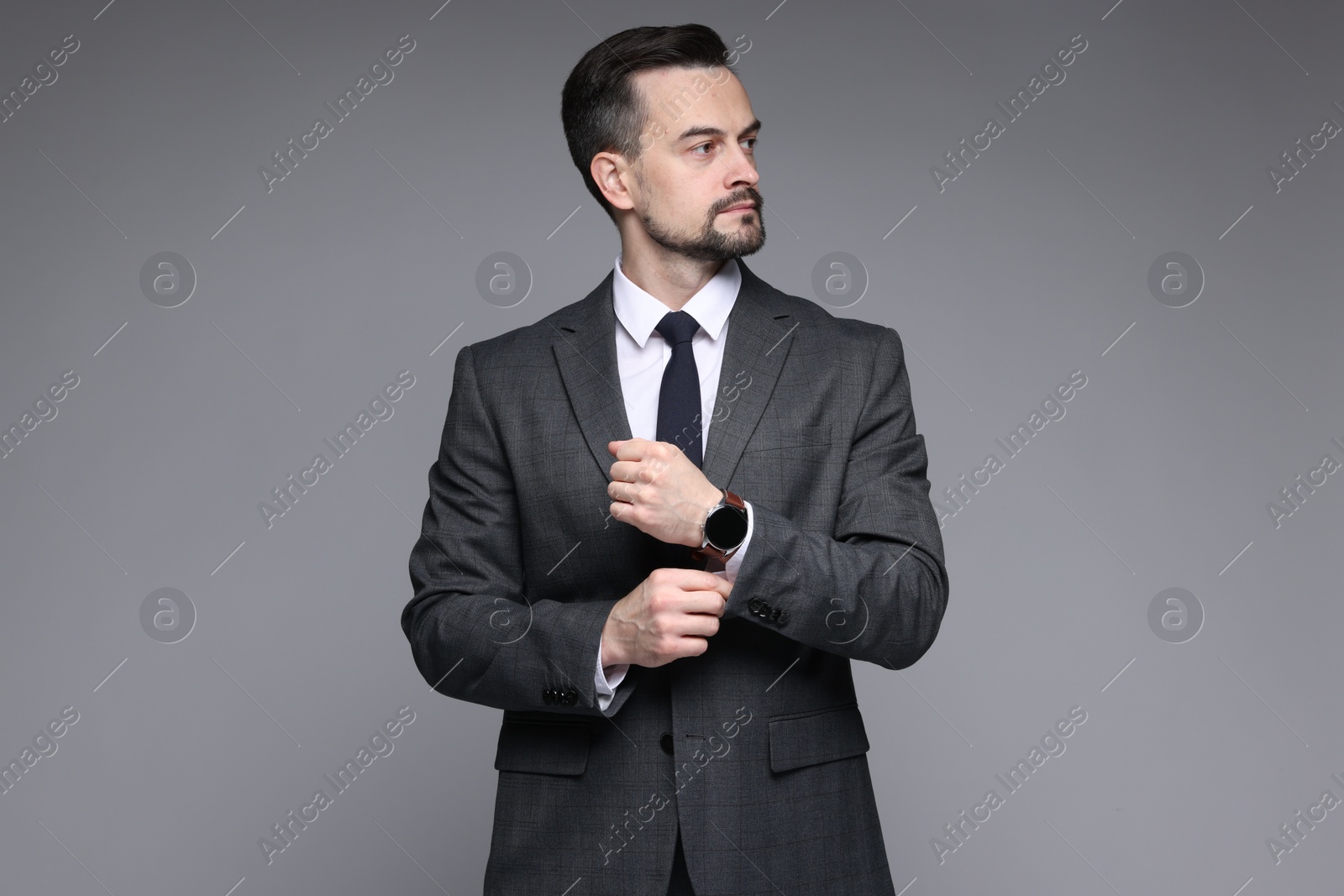 Photo of Handsome man in classic suit with stylish watch on grey background