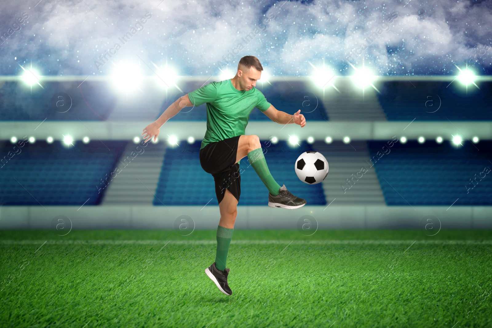 Image of Young man playing football under lights at stadium