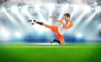 Image of Young man playing football under lights at stadium