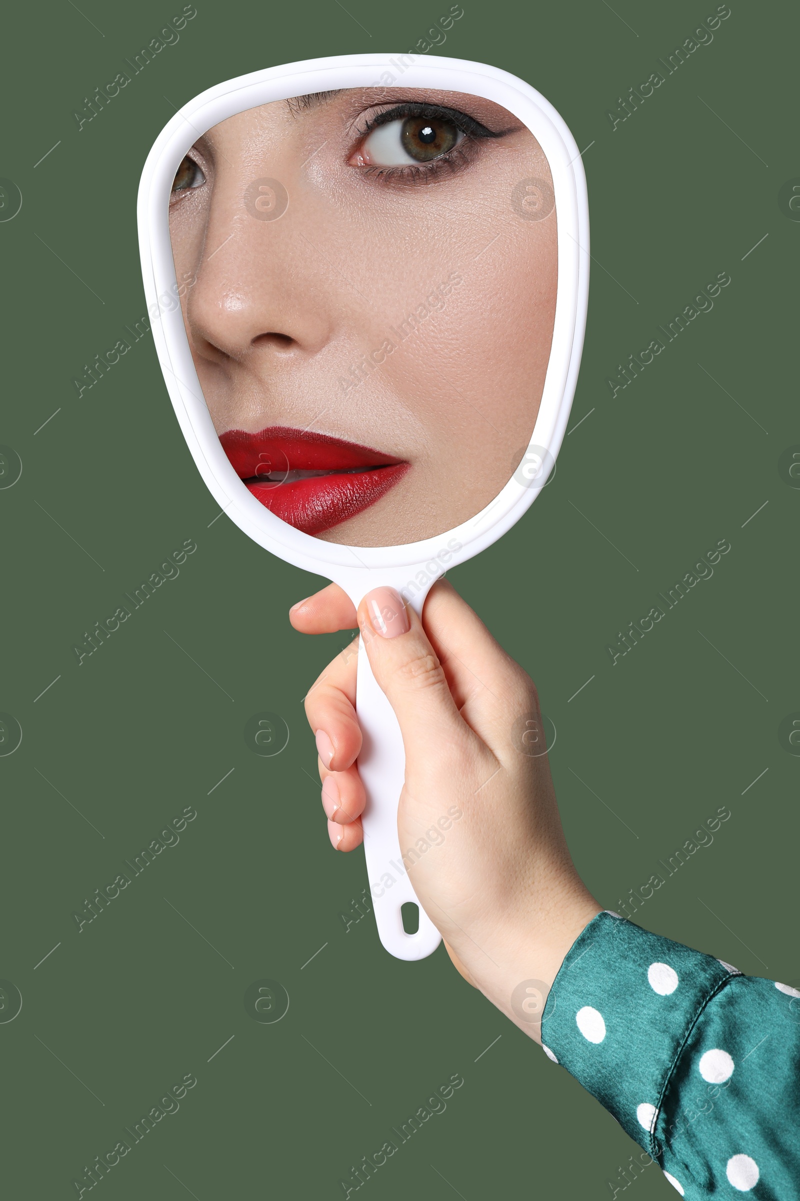 Image of Beautiful woman looking in handheld mirror on dark green background, closeup