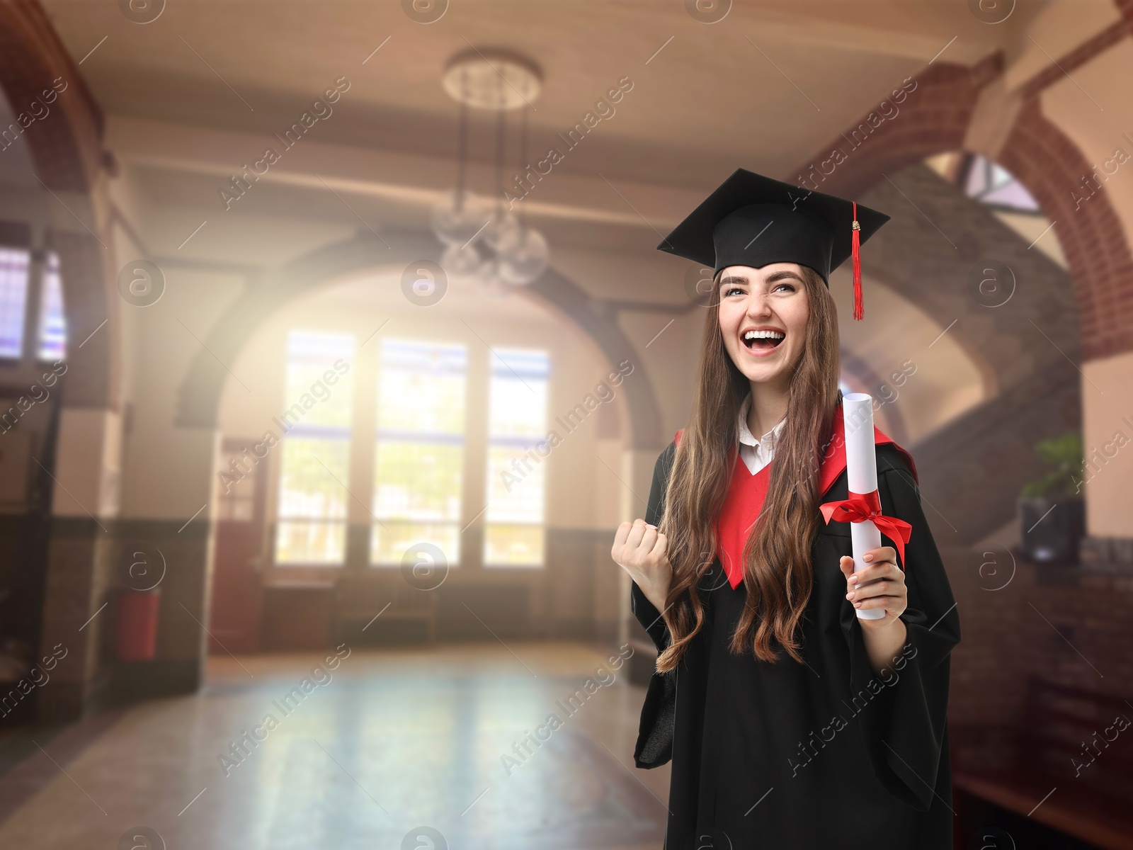 Image of Happy student in academic dress holding diploma after graduation in university